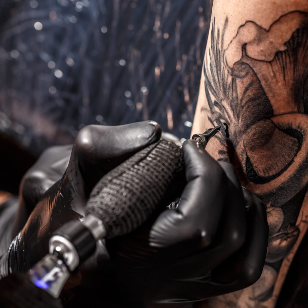 Close up image of the tattoo artist makes a tattoo on a man arm.